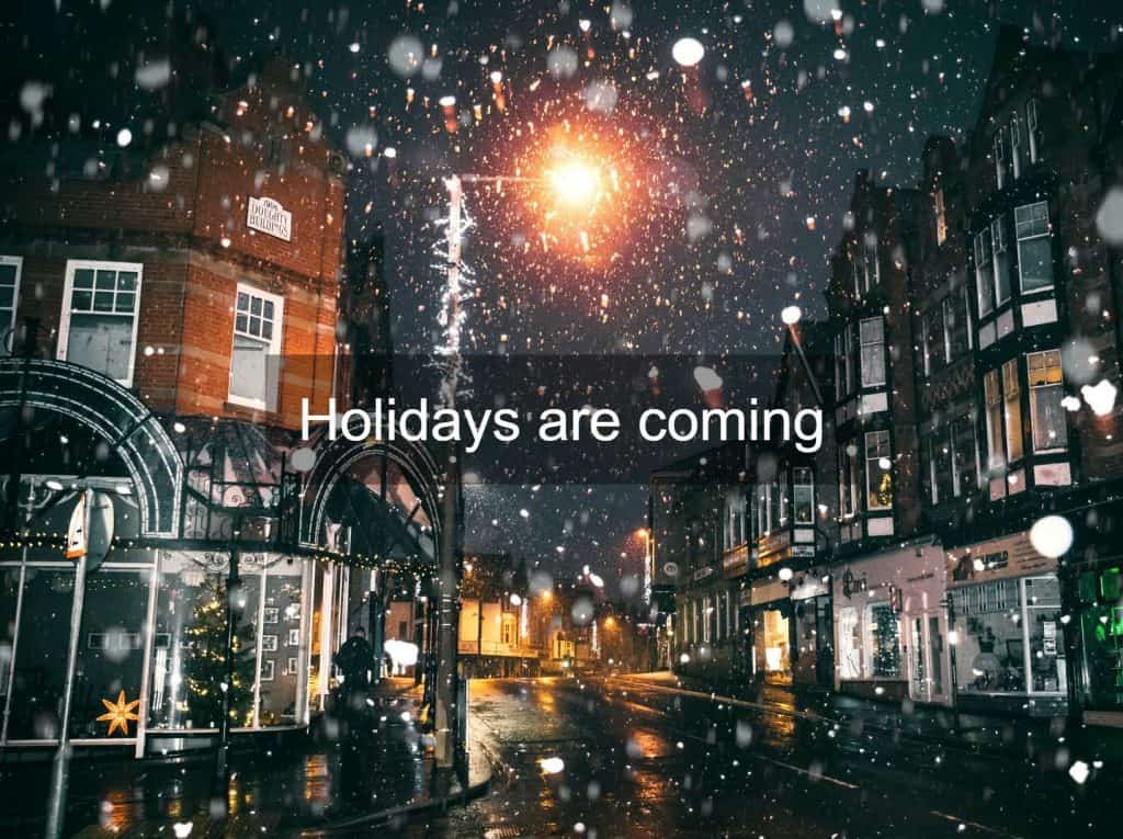 A street in winter while snow is falling and with a festive atmosphere